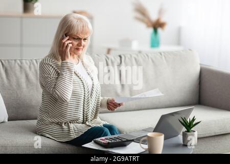 Reife Frau, die zu Hause am Handy arbeitet und spricht Stockfoto