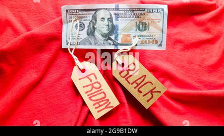 Etikettenpapier mit dem Text schwarzer freitag auf rotem Hintergrund mit amerikanischen Dollar. Shopping, Verkaufskonzept. Nahaufnahme, Kopierbereich. Stockfoto