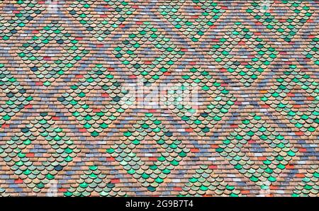 Das Dach besteht aus farbigen Fliesen. Altes Dach aus farbigen Fliesen. Hintergrund. Das Dach ist in einem Muster. Textur, Muster, Ornament aus alten bunten Stockfoto