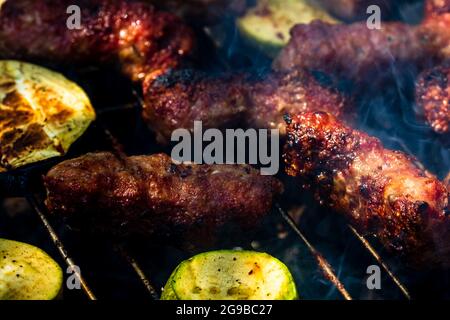 Eine Aufnahme aus einem hohen Winkel von Grillfleischbrötchen namens Mici oder mititei mit Gemüse auf dem Barbecues-Grill Stockfoto