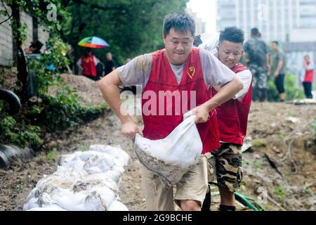 Changxing, Chinas Provinz Zhejiang. Juli 2021. Menschen tragen Sandsäcke zur Verstärkung der Flussufer im Landkreis Changxing der Stadt Huzhou, ostchinesische Provinz Zhejiang, 25. Juli 2021. Chinas nationales Observatorium setzte am Sonntag seine orangefarbene Warnung für den Taifun in-Fa fort, der gegen Sonntagmittag in Zhejiang landeinstürze. Quelle: Wu Zheng/Xinhua/Alamy Live News Stockfoto
