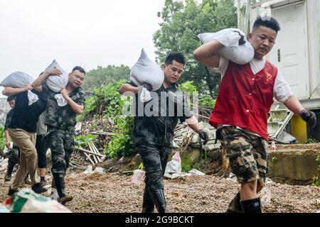 Changxing, Chinas Provinz Zhejiang. Juli 2021. Menschen tragen Sandsäcke zur Verstärkung der Flussufer im Landkreis Changxing der Stadt Huzhou, ostchinesische Provinz Zhejiang, 25. Juli 2021. Chinas nationales Observatorium setzte am Sonntag seine orangefarbene Warnung für den Taifun in-Fa fort, der gegen Sonntagmittag in Zhejiang landeinstürze. Quelle: Wu Zheng/Xinhua/Alamy Live News Stockfoto