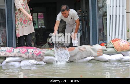 Zhoushan, Chinas Provinz Zhejiang. Juli 2021. Ein Mann versucht, Wasser aus seinem Haus in Zhoushan, der ostchinesischen Provinz Zhejiang, zu löschen, 25. Juli 2021. Chinas nationales Observatorium setzte am Sonntag seine orangefarbene Warnung für den Taifun in-Fa fort, der gegen Sonntagmittag in Zhejiang landeinstürze. Kredit: Chen Yongjian/Xinhua/Alamy Live Nachrichten Stockfoto