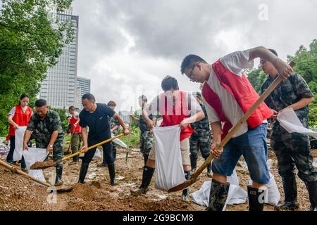 Changxing, Chinas Provinz Zhejiang. Juli 2021. Menschen füllen Sandsäcke, um die Flussufer im Landkreis Changxing der Stadt Huzhou, ostchinesische Provinz Zhejiang, zu stärken, 25. Juli 2021. Chinas nationales Observatorium setzte am Sonntag seine orangefarbene Warnung für den Taifun in-Fa fort, der gegen Sonntagmittag in Zhejiang landeinstürze. Quelle: Wu Zheng/Xinhua/Alamy Live News Stockfoto