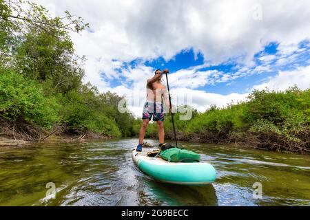 Abenteuerliche hispanische Erwachsene Athletic man Paddle Boarding Stockfoto