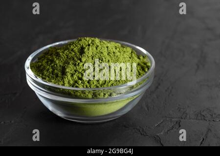 Grünes Chlorella-Pulver in einer Schüssel auf schwarzem Hintergrund. Algen natürliche Ergänzung. Spirulina-Pulver. Nahaufnahme. Stockfoto