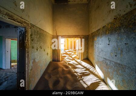 Verlassene Gebäude, die in der Geisterstadt Kolmanskop in der Nähe von Luderitz, Namib-Wüste, Namibia, von eindringenden Sand übernommen werden. Stockfoto