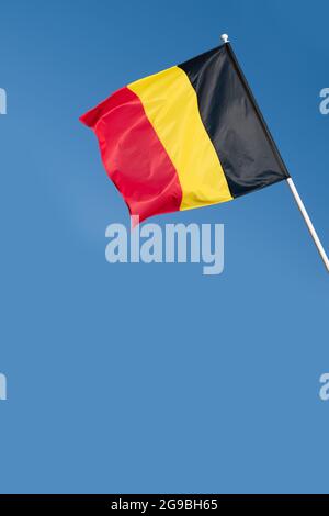 Flagge Belgiens auf blauem Himmel Hintergrund. Belgische Flagge winkt im Wind Stockfoto