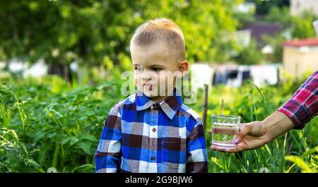 Das Kind trinkt sauberes Wasser in der Natur. Selektiver Fokus Stockfoto