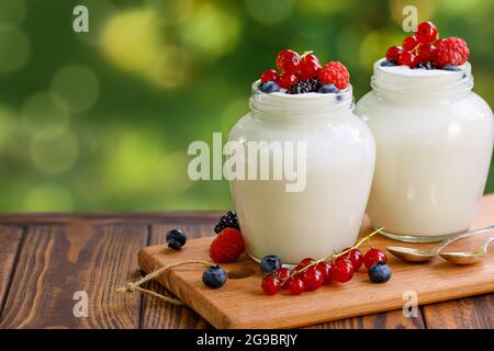 Joghurt und frische Beeren in zwei Gläsern auf dem Tisch im Freien Stockfoto