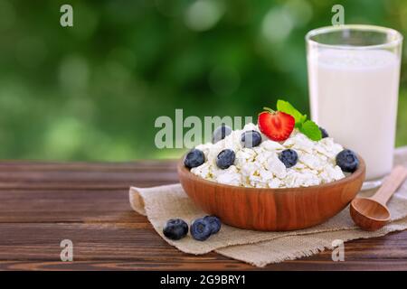Joghurt im Glas und Hüttenkäse mit frischen Heidelbeeren auf dem Tisch im Freien Stockfoto