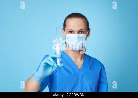 Junger Mann in Arztuniform mit Spritze Stockfoto