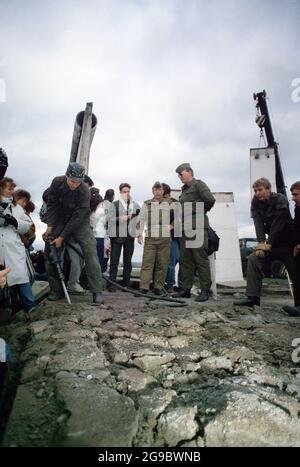 Die DDR-Polizei und westdeutsche Bürger beobachten, wie ein Arbeiter einen Teil der Berliner Mauer am Potsdamer Platz, 1989, demontierte Stockfoto