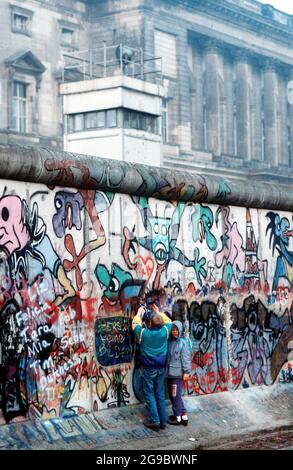 Westdeutsche Kinder versuchen, ein Stück der Berliner Mauer als Souvenir abzuspalten. Ein Teil der Mauer wurde bereits am Potsdamer Platz, 1989, abgerissen Stockfoto