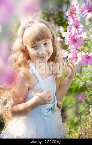 Porträt eines 10-jährigen kleinen Mädchens in einem blühenden Rosengarten. Nette schöne niedliche Baby Spaß mit Blumen im Park an einem sonnigen Sommertag. H