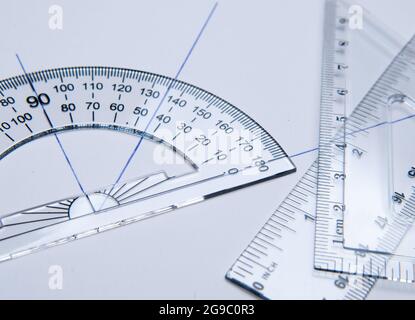 Schoolmaterialien für das Zeichnen: Fase, Quadrat und Winkelmesser auf weißem Papier. Zurück zur Schule Stockfoto