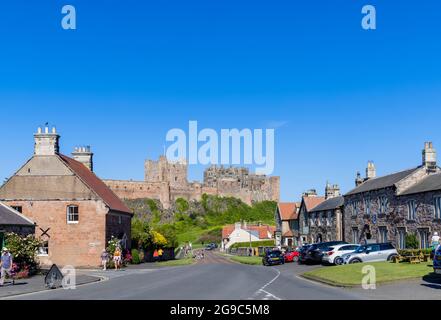 Das ikonische Bamburgh Castle, ein denkmalgeschütztes Gebäude an der Nordostküste Englands, das vom Dorf Bamburgh in Northumberland auf einem sonnigen Tal aus gesehen wird Stockfoto