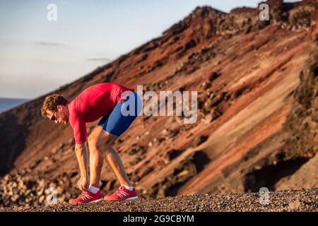 Laufsportler, der sich für das Training von Herz-Kreislauf-Übungen vorbereitet, indem er Laufschuhe mit Spitze bindet, um sich auf das Outdoor-Trailrennen in der Berglandschaft vorzubereiten. Sportmann Stockfoto