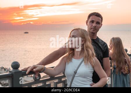 Eine junge Familie mit einem Kind am Ufer des Meeres bei Sonnenuntergang genießen ihren Urlaub. Ein wunderschöner Ort mit Atmosphäre. Stockfoto