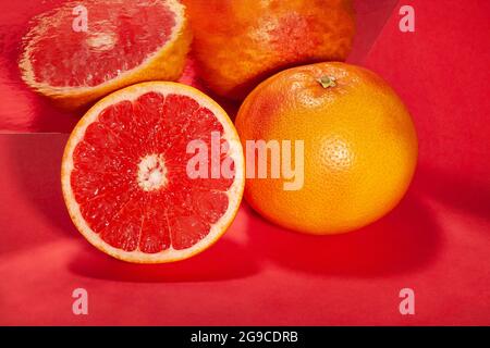 In Scheiben geschnittene, verspiegelte Grapefruit auf rotem Hintergrund Stockfoto