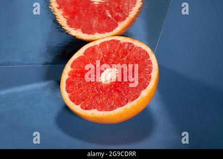 In Scheiben geschnittene, verspiegelte Grapefruit auf blauem Hintergrund Stockfoto