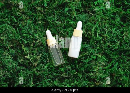 Set aus Serum-Tropfflaschen auf Mooshintergrund. Flach liegend, Draufsicht. Natürliche organische Hautpflegekosmetik. Stockfoto