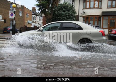 Ein Auto fährt durch eine Regenpfütze auf einer Straße in Ost-London nach einer Sturzflut ?heute Nachmittag.? Extreme Hitze in der Vorwoche hat sich den kühleren Temperaturen und dem stürmischen Wetter in England zugegeben.? ?ein bernsteinfarbenes Gewitterwarnsystem ist für viel von Südostengland im Platz?.? Stockfoto