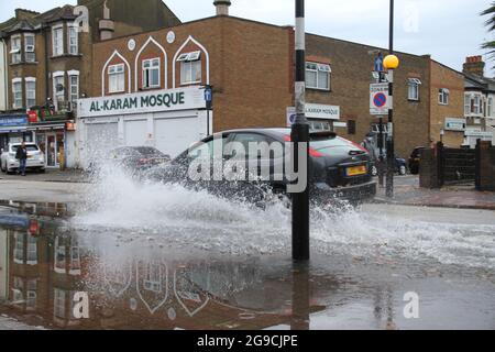 Ein Auto fährt durch eine Regenpfütze auf einer Straße in Ost-London nach Sturzfluten ?heute Nachmittag.? Extreme Hitze in der Vorwoche hat sich den kühleren Temperaturen und dem stürmischen Wetter in England zugegeben.? ?ein bernsteinfarbenes Gewitterwarnsystem ist für viel von Südostengland im Platz?.? Stockfoto