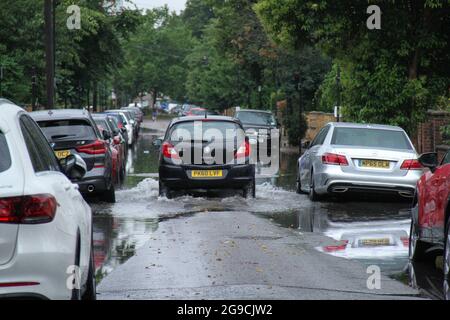 Ein Fahrzeug fährt durch eine Regenpfütze auf einer Straße im Osten Londons nach einer Sturzflut – heute Nachmittag.? Extreme Hitze in der Vorwoche hat sich den kühleren Temperaturen und dem stürmischen Wetter in England zugegeben.? ?ein bernsteinfarbenes Gewitterwarnsystem ist für viel von Südostengland im Platz?.? Stockfoto