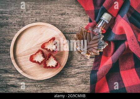 Ahornsirup Flasche aus Quebec mit Geschenk Süßigkeiten weichen Zucker Draufsicht auf rustikalem Holzhintergrund für Touristen Souvenir. Kanada Sorte EIN Bernstein süß Stockfoto