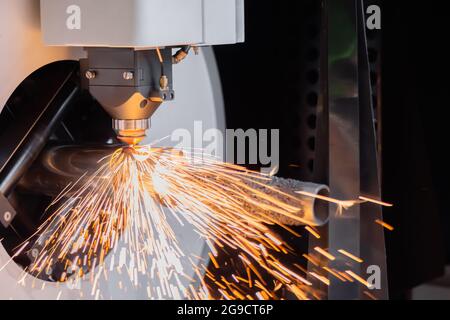 Laserschneidmaschine arbeitet mit zylindrischem Metallwerkstück mit Funken Stockfoto