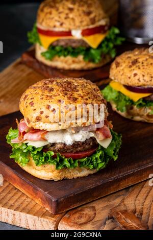 Eine vertikale Aufnahme köstlicher, farbenfroher Hamburger, die nebeneinander auf Holzbrettern platziert werden Stockfoto