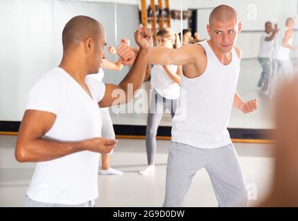 Männer üben grundlegende Bewegungen während des Selbstverteidigungskurses im Fitnessstudio Stockfoto