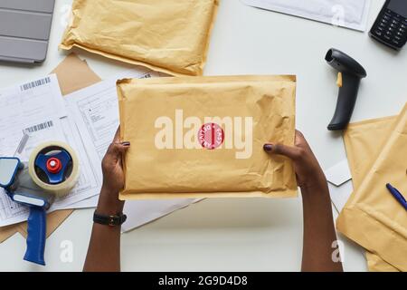 Draufsicht auf weibliche Hände, die das Paket beim Lieferservice über den Arbeitsplatz halten, Platz kopieren Stockfoto