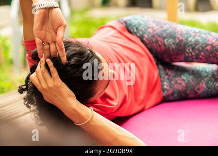 Braunhaariges Mädchen, das im Hausgarten Yoga macht, trägt ein rotes Sport-T-Shirt Stockfoto