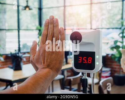 Mit der digitalen automatischen Body-Measuring-Temperaturkontrollmaschine die Temperatur vor dem Betreten des Cafés manuell überprüfen. Digitales Thermometer Maschine Infrarot Stockfoto