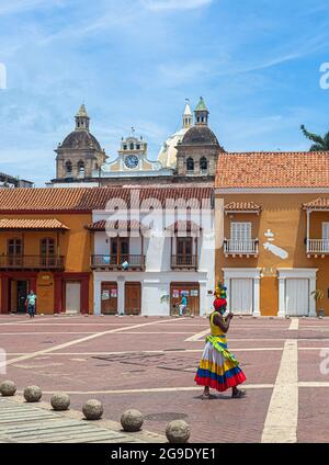 Eine Palenquera in ihrer traditionellen Tracht, die entlang der Plaza de la Aduana, Cartagena de Indias, Kolumbien, geht. Stockfoto