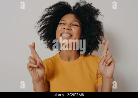 Kopf Schuss lächelnd schönen afrikanischen Mädchen mit geschlossenen Augen über die Finger wünschen viel Glück Stockfoto