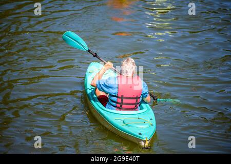 Ältere Männer bevorzugen Outdoor-Aktivitäten für einen gesunden Lebensstil, um die Gesundheit zu verbessern Ruhepaddeln auf dem Kajak auf dem Wasser eines Lacamas Lake umrahmt von Stockfoto