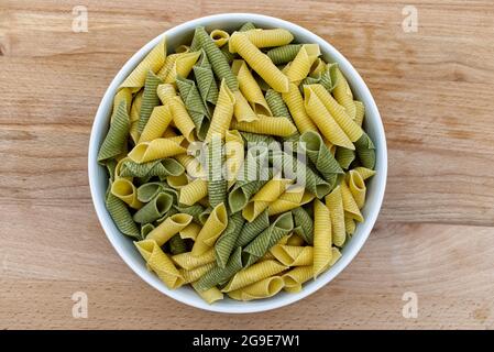 Frische, roh gefärbte Pasta. Italienische Maccheroni al pettine auf Holztisch. Blick von oben Stockfoto