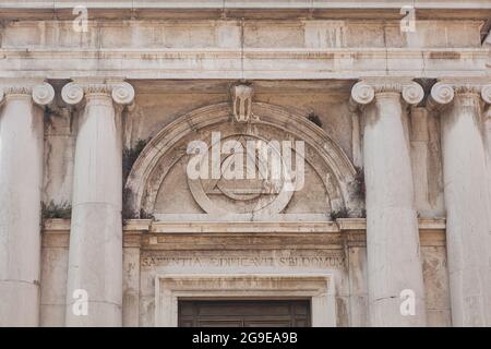 Massonisches Augenschild im Dreieck auf dem Gebäude der Kirche St. Magdalena, Canaregio District, Venedig, Italien. Der Text auf dem Portal über dem Eingang in lateinischer Sprache bedeutet: Weisheit hat ein Haus gebaut Stockfoto