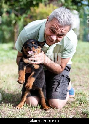 Mann und Welpe Rottweiler vor weißem Hintergrund Stockfoto