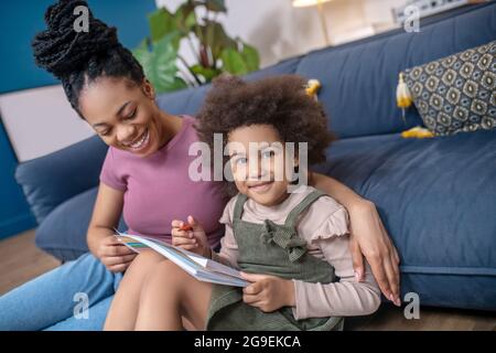 Fröhliche dunkelhäutige Mutter und Tochter malen zu Hause Stockfoto