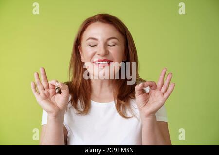 Fast perfekt. Nahaufnahme friedlich entspannt Rotschopf glücklich Frau geschlossen Augen rein erfreut Lächeln zeigen zen Frieden Zufriedenheit Geste meditieren Stockfoto