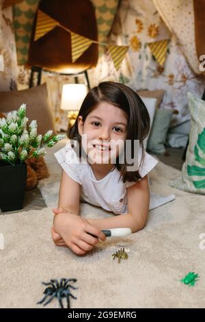 Mädchen spielt mit Lupe und Spielzeugkäfer Stockfoto