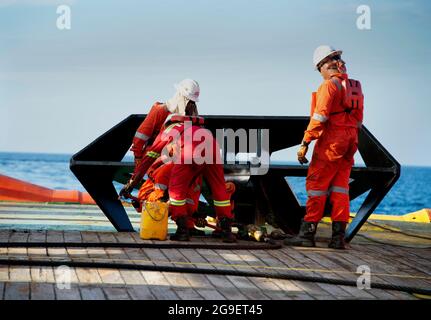 Die Schiffsbesatzung, die während des Frachtumschlags an Deck für die Aufbockvorrichtung auf See arbeitet Stockfoto