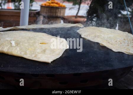 Street Food: Pfannkuchen. Einheimische Frau kocht Pfannkuchen auf Blech, in das sie Käse, Spinat oder Kartoffeln steckt. Pfannkuchen Mit Selektivem Fokus. Stockfoto