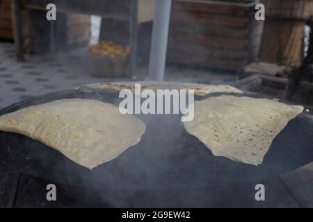 Street Food: Pfannkuchen. Einheimische Frau kocht Pfannkuchen auf Blech, in das sie Käse, Spinat oder Kartoffeln steckt. Pfannkuchen Mit Selektivem Fokus. Stockfoto