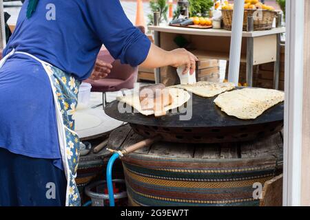 Street Food: Pfannkuchen. Einheimische Frau kocht Pfannkuchen auf Blech, in das sie Käse, Spinat oder Kartoffeln steckt. Pfannkuchen Mit Selektivem Fokus. Stockfoto