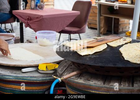 Street Food: Pfannkuchen. Einheimische Frau kocht Pfannkuchen auf Blech, in das sie Käse, Spinat oder Kartoffeln steckt. Pfannkuchen Mit Selektivem Fokus. Stockfoto